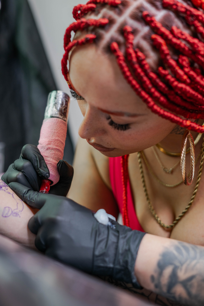 Sandy de perfil tatuando un antebrazo en el estudio
