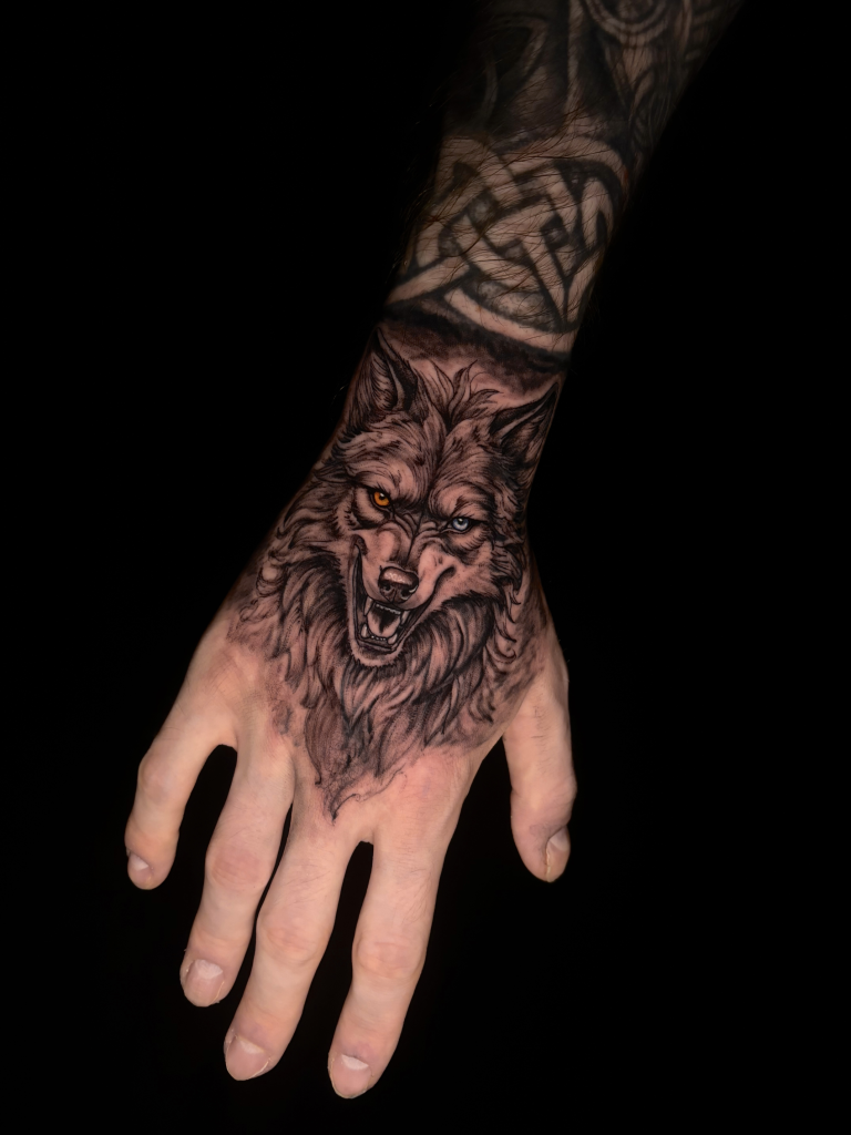 Tatuaje de un lobo en blanco y negro que cubre el dorso de la mano y la muñeca