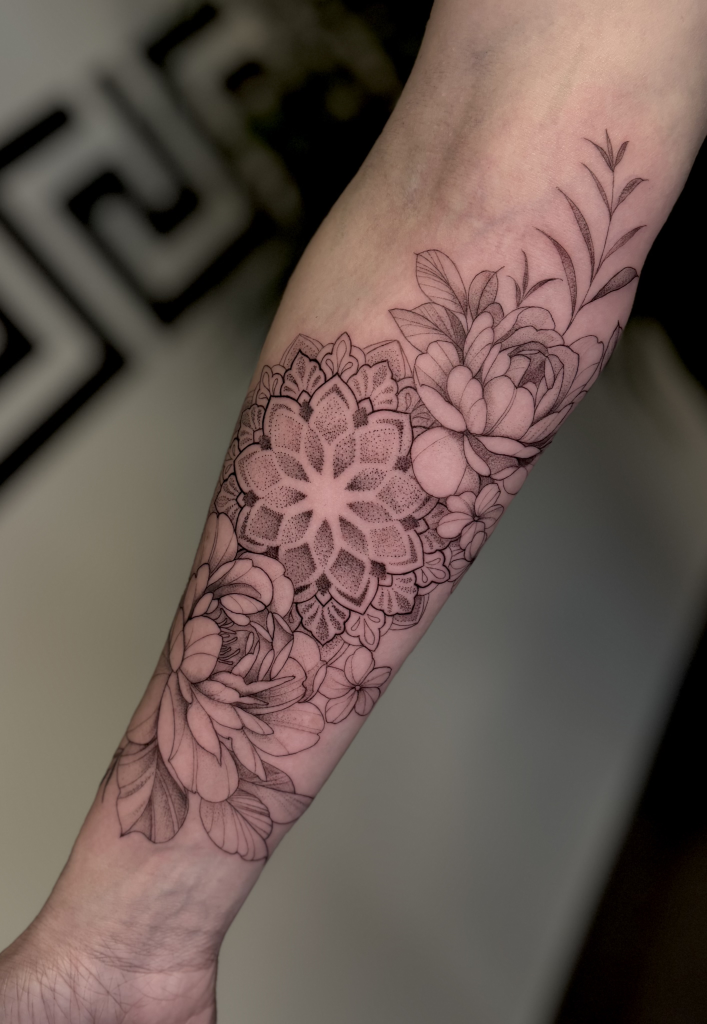 Media manga de línea fina en el antebrazo, con un mandala rodeado de flores