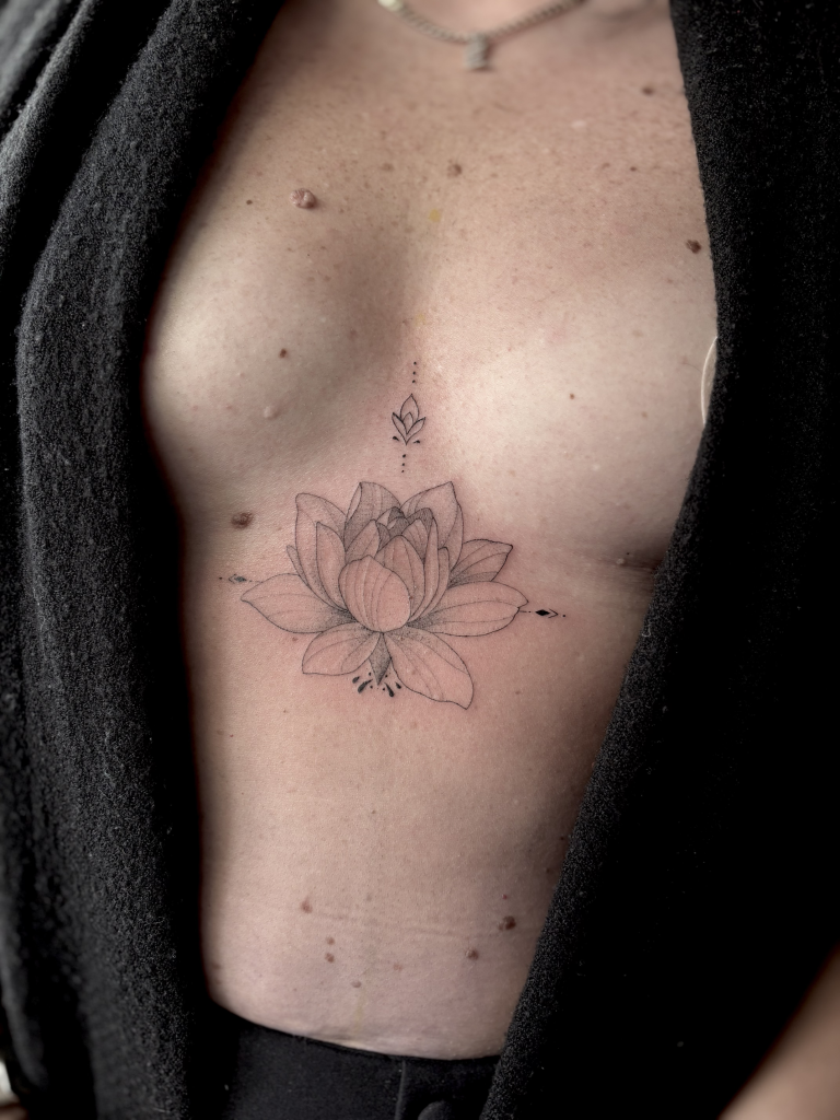 Flor de loto de línea fina tatuada en el esternón