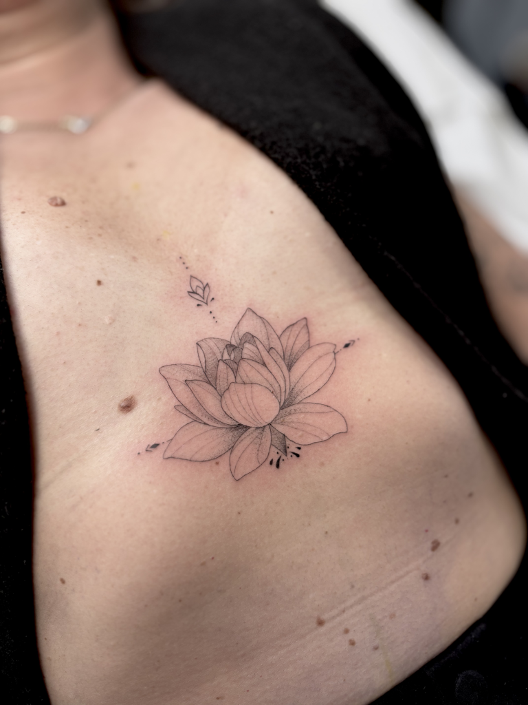 Flor de loto de línea fina tatuada en el costado, bajo el pecho