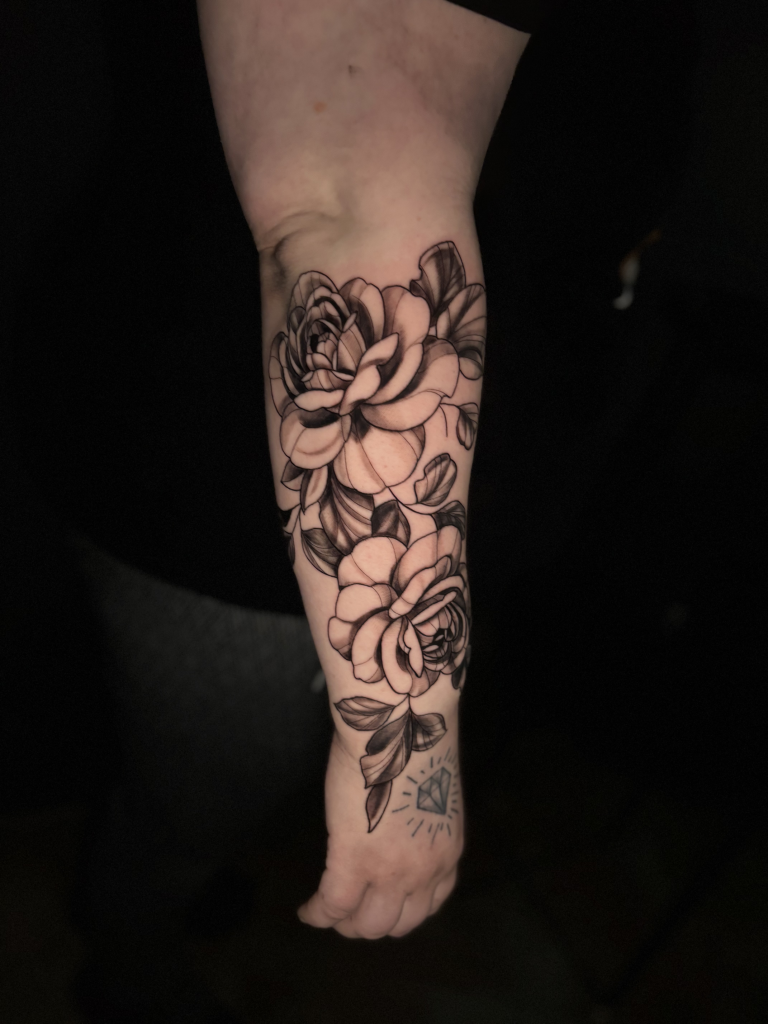 Manga de rosas en blanco y negro tatuada en el antebrazo