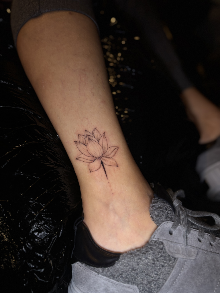 Flor de loto de línea fina tatuada en el tobillo