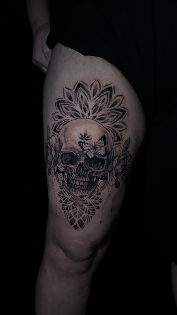 Tatuaje de una calavera sobre un mandala en el muslo