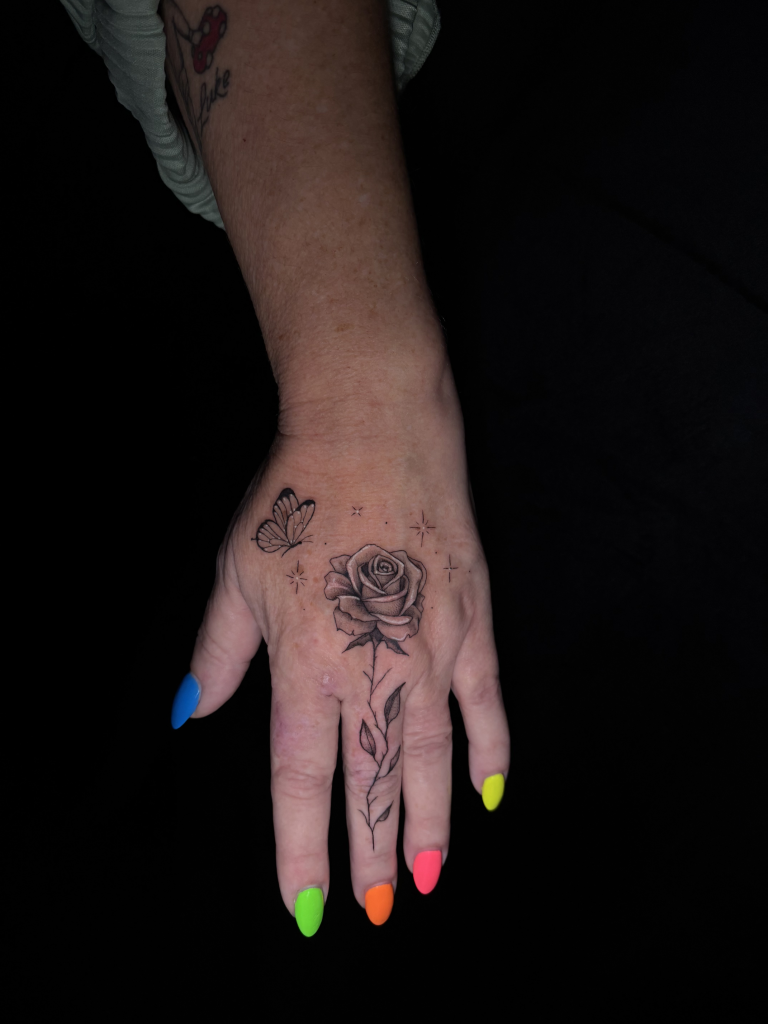 Rosas de línea fina tatuadas en los dedos y el dorso de la mano